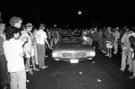 A car drives through a crowd during the homecoming riots, St. Cloud State University