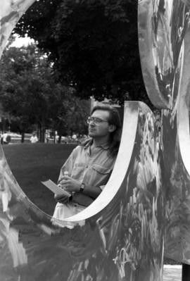 A man stands next to the Perspectives artwork, St. Cloud State University