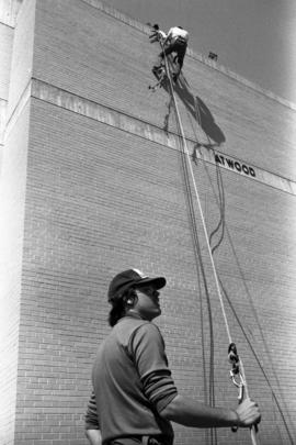 Al Cottingham climbs an Atwood Memorial Center (1966) wall while Joel Lindmeer looks on, St. Cloud State University