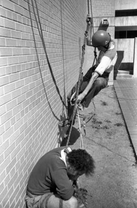 Al Cottingham begins to climb an Atwood Memorial Center (1966) wall while Joel Dhien looks on, St. Cloud State University