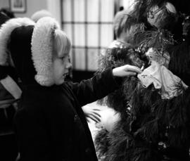 A child inspects an ornament on the president's Christmas tree in Whitney House (1956), St. Cloud State University