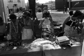 Women examine merchandise on a table, Lemonade Concert and Art Fair, St. Cloud State University