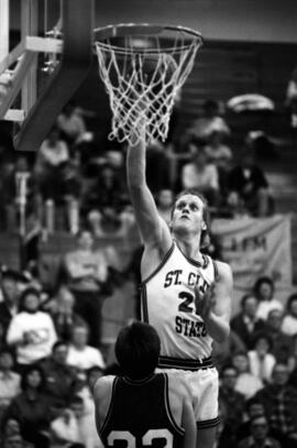 Basketball player Mark Harvey dunks a basketball during a game against Moorhead State University, St. Cloud State University