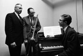 Kenton Frohrip and others gather at a piano, St. Cloud State University