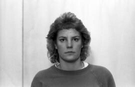 Black and white portrait of a person with short, curly hair wearing a plain sweatshirt, looking directly at the camera against a light-colored background.