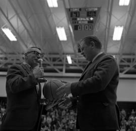 Ed Colletti presents St. Cloud State men's basketball coach Marlowe "Red" Severson with the game ball after St. Cloud State defeated Bemidji State, giving Severson his 200th victory at St. Cloud State