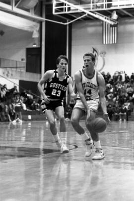 Basketball player Barry Wohler dribbes a basketball in a game against Gustavus Adolphus College, St. Cloud State University