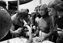 People look at moon rocks with a microscope at the Wick Science Center, St. Cloud State University