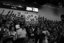 Woman holds a sign that reads "Lean on us Huskies" during a basketball game against Delta State University, St. Cloud State University