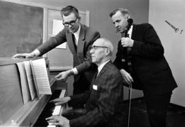 Harvey Waugh, James Flom, and James Johnson gather to play at a piano, St. Cloud State University