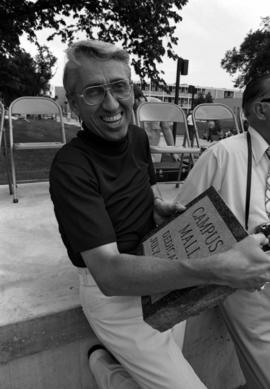 Ray Rowland holds the campus mall dedication plaque, St. Cloud State University