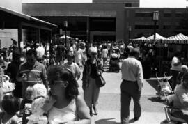 People walk on a sidewalk looking at vendors' booths, Lemonade Concert and Art Fair, St. Cloud State University