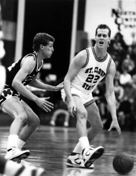 Basketball player Mark Harvey dribbles a basketball during a game, St. Cloud State University