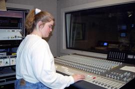 Woman runs an audio board in a studio, St. Cloud State University