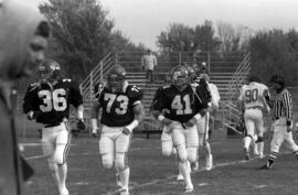 Mike Lambrecht and other football players run onto the field before a game with the University of Nebraska-Omaha