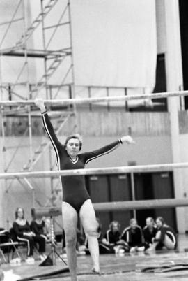 Woman gymnast competes in the uneven bars in a meet against Augsburg College, St. Cloud State University