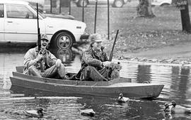 Dave Anderson and Jim Buisch sit in a duck boat in a flooded campus parking lot, St. Cloud State University