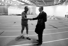 St. Cloud State president Charles Graham greets Wheelock Whitney after his run in the new Halenbeck Hall (1965) fieldhouse