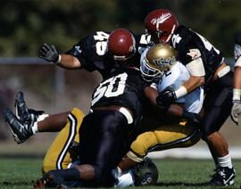 Three football players tackle another, St. Cloud State University