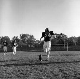 Football player Scott Quisling kicks a football during practice, St. Cloud State University