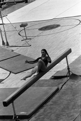 Woman gymnast balances on her back on a balance beam in a meet against Augsburg College, St. Cloud State University