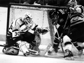 University of Minnesota player Chris McAlpine and goalie Jeff Moen try to stop St. Cloud State University player Adam Rodak at the WCHA hockey championship game in Milwaukee