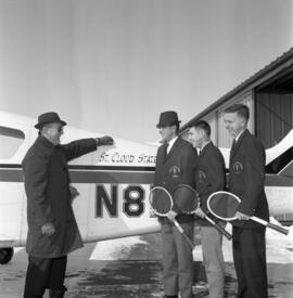 Men's tennis players stand in front of a plane, St. Cloud State University