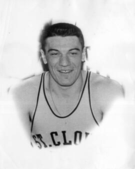 Black and white portrait of a person with short hair wearing a sleeveless athletic jersey that reads "ST. CLOUD." The individual is looking directly at the camera with a neutral expression. The background is plain and slightly blurred.