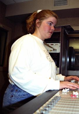 Woman runs an audio board in a studio, St. Cloud State University