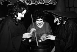 Witches stand at a cauldron at the haunted Halloween Carnegie library event, St. Cloud State University