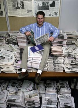 Editor Mike Koehler sits on copies of the Chronicle in the Chronicle newsroom, St. Cloud State University