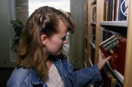 Woman looks at a book on a shelf, Aalborg, Denmark, St. Cloud State University