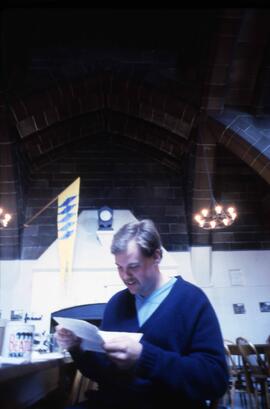 Man reads a letter in Alnwick Castle's dining hall, St. Cloud State University