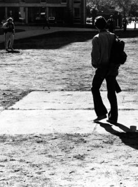 A student walks across a lawn, St. Cloud State University