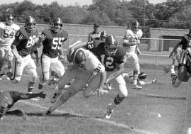 Football player Keith Nord (#12) makes a tackle against a University of South Dakota ball carrier, St. Cloud State University