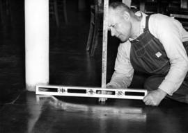 Man measures sagging floor, Old Model School (1906), St. Cloud State University