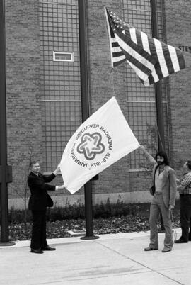 President Charles Graham shows off the bicentennial flag in front of Stewart Hall (1948), St. Cloud State University