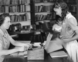 A librarian helps a child at Riverview (1913), St. Cloud State University