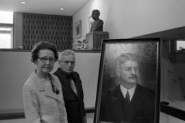 L. Ferne Atwood and Edwin Cates stand next to a portrait of Clarence Atwood,