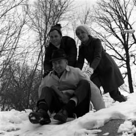 Travis Kent on a sled being pushed by Sno-Daze co-chairs Chuck Carlson and Diane Heacox