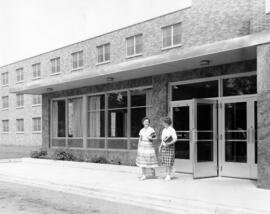 Two women stand in front of Mitchell Hall (1958), St. Cloud State University