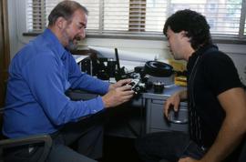 Richard Hill and another man examine a camera, St. Cloud State University