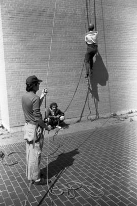 Al Cottingham climbs an Atwood Memorial Center (1966) wall while Joel Lindmeer and Joel Dhien look on, St. Cloud State University