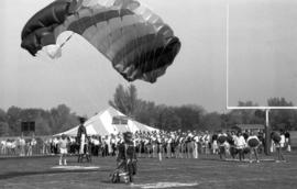 A man parachutes on the field before the homecoming football game