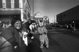 Woman poses with her husky dog in the homecoming parade while the Husky mascot stands nearby in downtown St. Cloud, St. Cloud State University