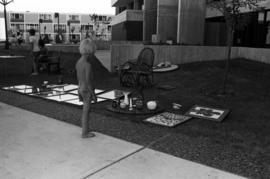 A boy looks at merchandise laying on the lawn, Lemonade Concert and Art Fair, St. Cloud State University