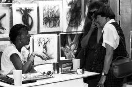 Two women talk to a vendor, Lemonade Concert and Art Fair, St. Cloud State University