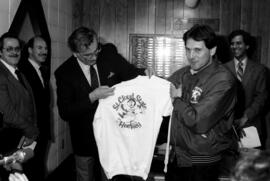 St. Cloud State hockey coach John Perpich gives a sweatshirt to Minnesota governor Rudy Perpich